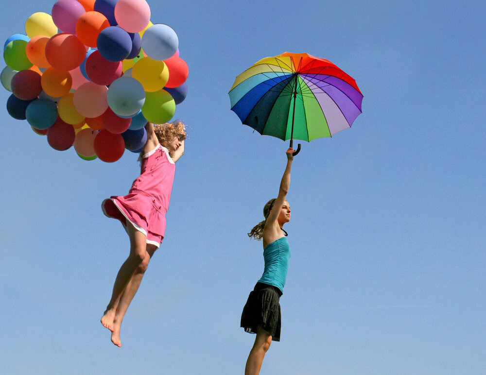 Zwei fliegende Frauen mit Luftballons und Schirm